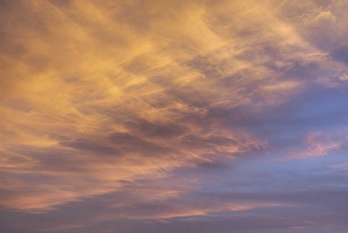 The sky at the exact moment of the autumn equinox, warm gold clouds tipping into cool violet-pink toward dusk.
